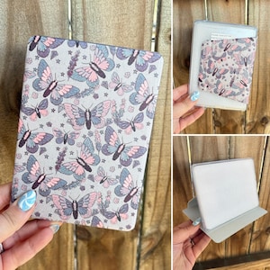 May include: A gray tablet case featuring a repeating pattern of butterflies in shades of pink, blue, and purple. The case is shown open and closed, with a matching screen protector. The case is designed to protect a tablet.