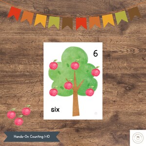 Könnte beinhalten: Aquarellillustration eines Baumes mit sechs roten Äpfeln, beschriftet mit der Zahl 6 und dem Wort "sechs". Das Bild ist Teil einer "Hands-On Counting 1-10"-Serie, mit einem Banner aus bunten Flaggen darüber.