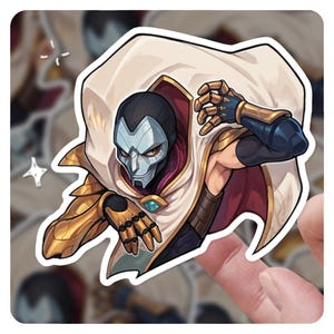 May include: A sticker depicting a character with a silver mask, black head covering, and a white cape with red lining. The character has gold armour on the arms and shoulders, and a blue gem on the chest. The sticker is on a background of other stickers.