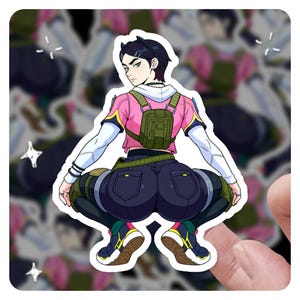 May include: A sticker depicting a person in a squatting pose, wearing a pink and white top, dark blue trousers, and trainers. The person has short black hair and a small backpack. The sticker has a white border and is held by a finger.