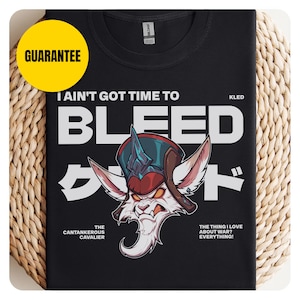 May include: Black t-shirt featuring a cartoon character with a red and blue helmet and the text "I Ain't Got Time To Bleed". Additional text includes "Kled", "The Cantankerous Cavalier", and "The thing I love about war? Everything!".