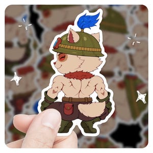 May include: A sticker featuring a cartoon character with tan fur, wearing a green helmet with a blue plume, goggles, and brown pants. The character has a red neck ruff and is flexing its muscles. The sticker is held by a hand.