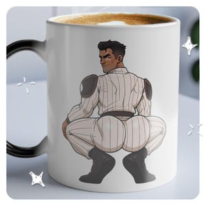 Könnte beinhalten: Eine weiße Keramik-Kaffeetasse mit schwarzem Henkel. Die Tasse zeigt eine Comic-Illustration einer Person, die eine weiße und graue gestreifte Baseballuniform trägt und mit dem Rücken zum Betrachter hockt. Die Person hat braunes Haar und braune Augen.