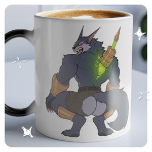 Könnte beinhalten: Eine weiße Keramik-Kaffeetasse mit schwarzem Henkel zeigt eine farbenfrohe Illustration einer wolfartigen Kreatur mit einem grün leuchtenden Gerät auf dem Rücken. Die Kreatur trägt braune Shorts und hat einen grimmigen Ausdruck.