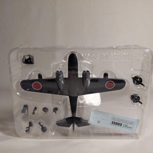 以下が含まれることがあります： 翼に赤い円のマークが付いた濃い灰色の模型飛行機で、透明なプラスチック容器に梱包されています。 モデルには別々の部品が含まれており、ラベルには「GOOSE」という文字が記載されています。