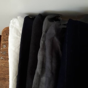 May include: Five fabric swatches in different colours. The swatches are arranged vertically, with the white swatch at the top and the dark blue swatch at the bottom. The swatches are all the same size and are made of a soft, textured fabric.