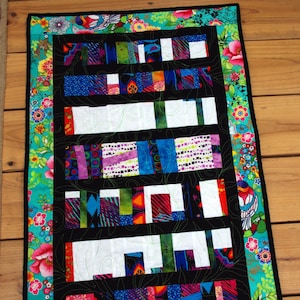 This unique, scrappy, quilt was made from the left over fabric of my last quilt. Bold and bright colors surrounded by a cheerful border. 20"x30.5"