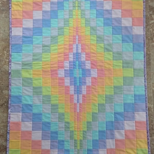 May include: A pastel rainbow quilt with a diamond pattern. The quilt is made of squares of different pastel colors, including pink, blue, yellow, and green.