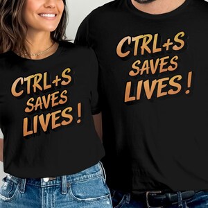 May include: Two black t-shirts with the text "CTRL+S SAVES LIVES!" in orange and yellow lettering. The shirts are worn by two people.