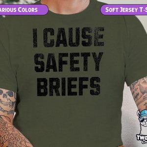 May include: A green t-shirt with the text "I cause safety briefs" in black. The shirt is made of a soft jersey material. The text is in a distressed font.