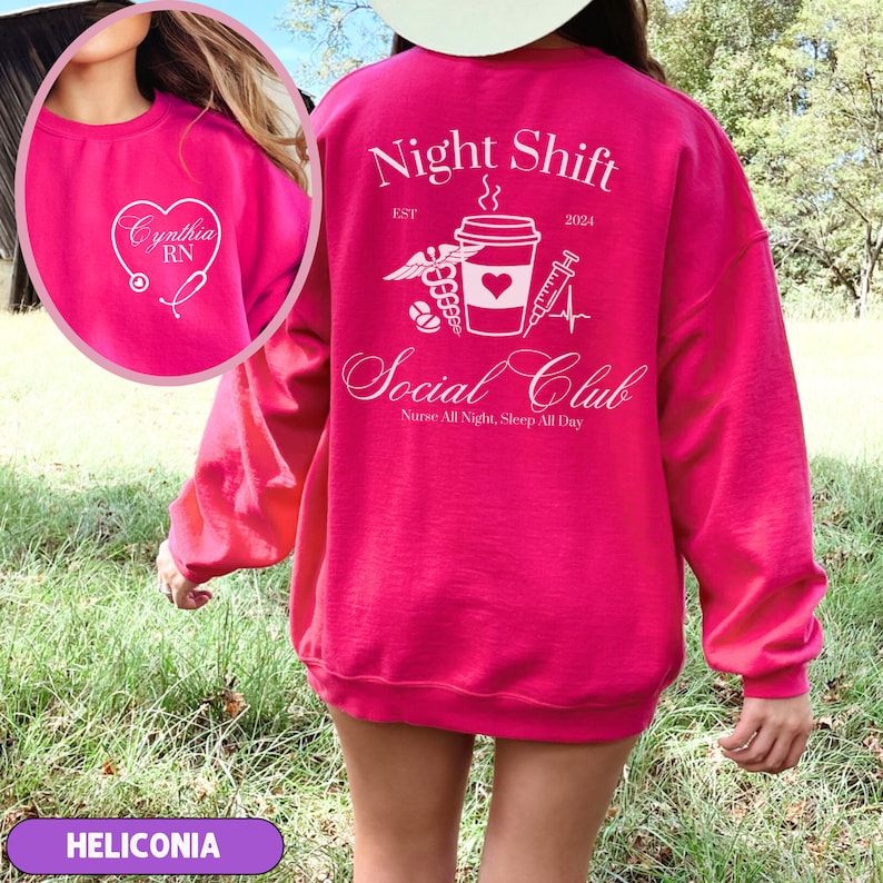 K&ouml;nnte beinhalten: Rosafarbener Pullover mit einem wei&szlig;en Grafikdesign, auf dem "Night Shift Social Club" mit einer Kaffeetasse, einem Stethoskop und einer Spritze steht. Der Text "EST 2024" befindet sich &uuml;ber dem Grafikdesign und der Text "Nurse All Night, Sleep All Day" darunter. Der Pullover hat auch ein wei&szlig;es Herz mit dem Text "Cynthia RN" auf der Vorderseite.