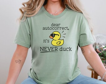 May include: A green t-shirt with a graphic of a rubber duck wearing sunglasses and the text "dear autocorrect, it's NEVER duck".