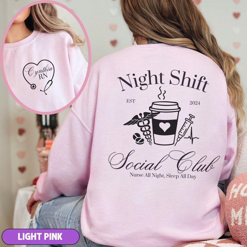 K&ouml;nnte beinhalten: Hellrosafarbener Pullover mit dem Text "Night Shift" und "Social Club" auf der R&uuml;ckseite. Das Design beinhaltet eine Kaffeetasse, ein Stethoskop, eine Spritze und ein Herz. Der Text "EST 2024" ist ebenfalls auf der R&uuml;ckseite aufgedruckt.