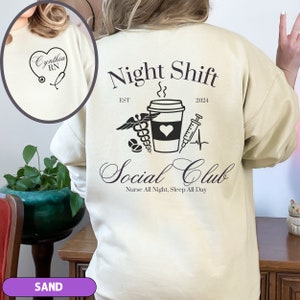 K&ouml;nnte beinhalten: Sandfarbener Sweatshirt mit dem Text "Night Shift" und "Social Club" auf der R&uuml;ckseite. Der Text ist schwarz und das Design beinhaltet eine Kaffeetasse, ein Stethoskop, eine Spritze und ein Herz.