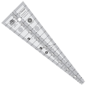May include: A clear plastic 15-degree triangle ruler with markings in inches and degrees. The ruler is designed by Erin Underwood and has a 24-petal design on the top.