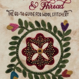 May include: A book cover with the title "Wool, Needle & Thread: The Go-To Guide for Wool Stitchery" in cursive script. The cover features a red flower with green leaves, a traditional wool applique design.