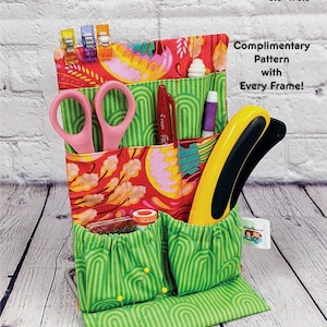 May include: A fabric sewing organizer with multiple pockets, holding scissors, pens, and other sewing tools. The organizer is 5.5" x 8.5" and features a red floral and green striped pattern. Text on the organizer reads "Sew Organized".