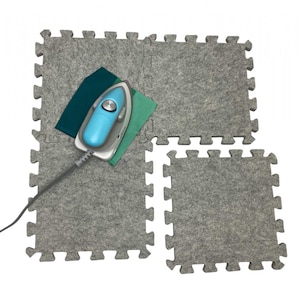 May include: A blue and gray iron on a gray interlocking puzzle mat. The mat is made of felt and has a textured surface.