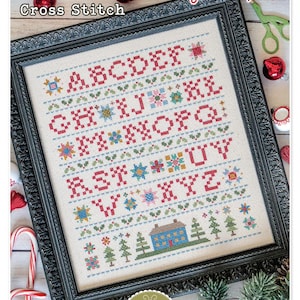 May include: A cross stitch pattern featuring a colorful alphabet with a small house and trees at the bottom. The pattern is framed in a black frame with a decorative border. The text "Home Town Holiday Sampler" and "Cross Stitch" is at the top of the image. The text "Designed by Lori Holt" and "Bee in my Bonnet Co." is at the bottom of the image.