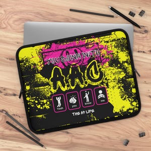 May include: Black laptop sleeve with a yellow and pink graffiti design. The text "You down with the A/C" is written in pink and white. The text "The A/C Life" is written in white. There are four icons with the text "Yeah", "You", "Know", and "Me".