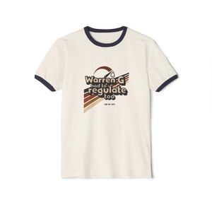 May include: A white t-shirt with a navy blue ringer. The shirt features a retro-style graphic with the text "Warren G had to regulate too" and the words "The OP Life" in smaller font.