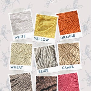May include: A collection of yarn samples in various colors, including white, yellow, orange, wheat, beige, camel, taupe, coffee, and Mexican rose. The yarn is displayed in individual frames with the color name written below each sample.
