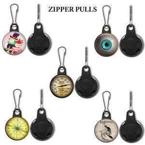 May include: Set of six zipper pulls with different designs. The designs include a snowman, an eye, a gauge, a compass, and a witch on a broomstick. Each zipper pull has a black plastic backing.