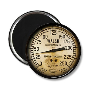May include: A vintage-style round gauge with a black face and white numbers. The gauge reads "WALSH CONSTRUCTION CO. LTD" and "SEATTLE-VANCOUVER". The gauge is labeled "WATER" and has a black needle.