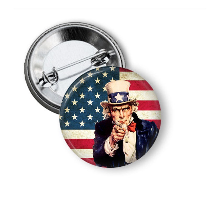 May include: A button featuring Uncle Sam pointing with the American flag in the background. The flag is red, white, and blue with a distressed look.