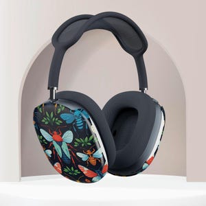 May include: Dark gray over-ear headphones with a colorful insect pattern on the earcups. The design features red, blue, and orange insects with green foliage against a black background. The headband and earcups are a solid dark gray color.