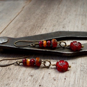 May include: A pair of dangle earrings with red and orange glass beads and a red flower charm.