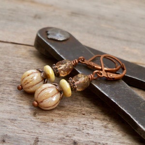 May include: Copper wire earrings with white and brown striped glass beads and clear glass beads with gold flecks.