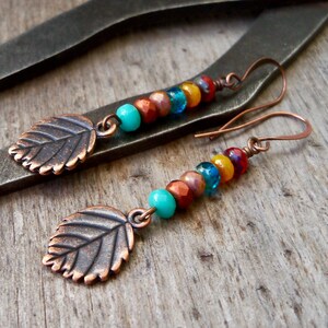 May include: A pair of copper leaf earrings with colorful glass beads in shades of turquoise, orange, yellow, and red.