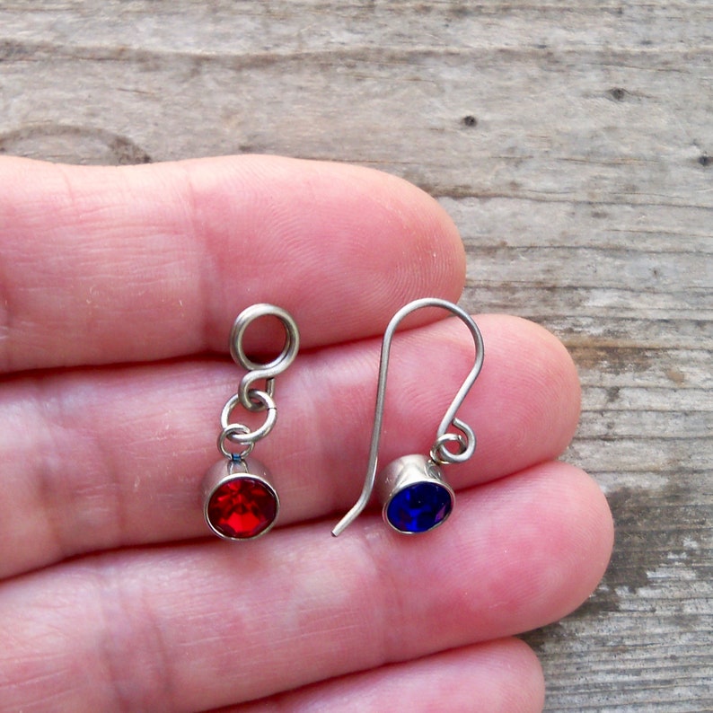 May include: A pair of silver earrings with red and blue crystal accents. The earrings are simple and elegant, perfect for everyday wear.