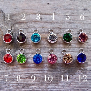 May include: Twelve silver charms with different colored crystal stones. The charms are numbered 1 through 12.