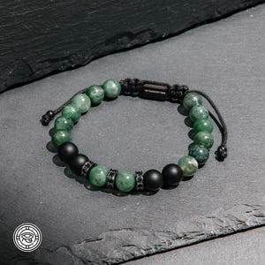May include: A beaded bracelet featuring alternating green mottled stone beads and matte black beads. The design includes small, cylindrical black metal spacers encrusted with tiny black crystals and a central black metal tag labeled MY HARMONY TREE.