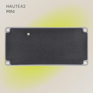 May include: A black metal pedal with the text "HAUTE42 MINI" printed on the top. The pedal has four screws on the sides.