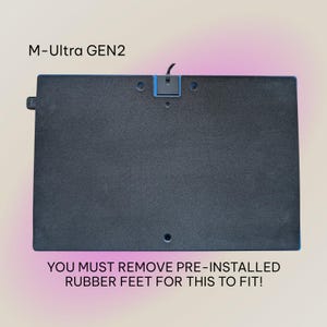 May include: A rectangular black device with blue trim and a small black cable. The text "M-Ultra GEN2" is at the top, and the text "YOU MUST REMOVE PRE-INSTALLED RUBBER FEET FOR THIS TO FIT!" is at the bottom.