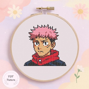 May include: Cross-stitch pattern of an anime character with pink hair, a red hooded jacket, and a serious expression. The design is framed in a wooden embroidery hoop. The text "PDF Pattern" is in the lower left corner.