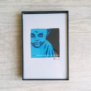 May include: A framed drawing of a blue-toned person with a quote that reads "elbow the time out of the way and make room for everything else." The drawing is signed "Todd!" with a red heart.