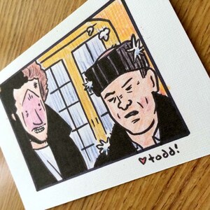 May include: A hand-drawn illustration of two men, one with a black beanie and the other with a red and white striped shirt. The man in the beanie has a serious expression, while the other man has a surprised look on his face. The illustration is in a comic book style and has a whimsical feel. The text "todd!" is written in red at the bottom of the image.