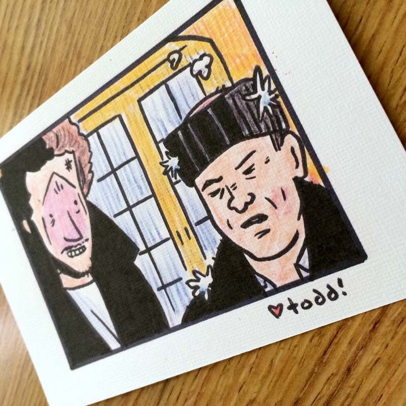 May include: A hand-drawn illustration of two men, one with a black beanie and the other with a red and white striped shirt. The man in the beanie has a serious expression, while the other man has a surprised look on his face. The illustration is in a comic book style and has a whimsical feel. The text "todd!" is written in red at the bottom of the image.