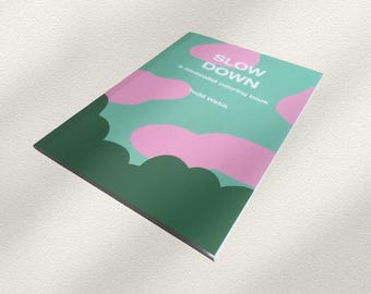 May include: A softcover coloring book titled SLOW DOWN, a minimalist coloring book by Todd Webb. The cover features a light blue background with abstract pink cloud shapes and dark green foliage patterns printed across the front surface.