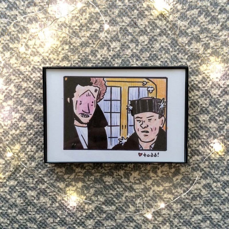 May include: A framed illustration of two men, one with a black jacket and the other with a black hat, with the text "&hearts; todd!" at the bottom.