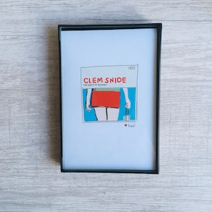May include: A framed print of a vintage album cover featuring a cartoon illustration of a woman in a red skirt and blue background. The album title is "Clem Snide" and the album name is "The Ghost of Fashion".