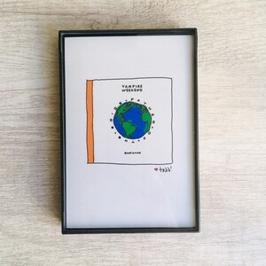 May include: A framed print of a hand-drawn album cover for Vampire Weekend's album "Father of the Bride". The cover features a globe with a green and blue color scheme, surrounded by a circle of text that reads "Father of the Bride". The album title is written in black text above the globe. The text "Softboi" is written in black text below the globe. The text "todd!" is written in red text below the album title.