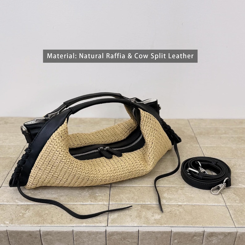 May include: A handbag crafted from natural raffia and black cow split leather, featuring a central zippered compartment, dual top handles, and a detachable black shoulder strap. The text Material: Natural Raffia & Cow Split Leather is visible.