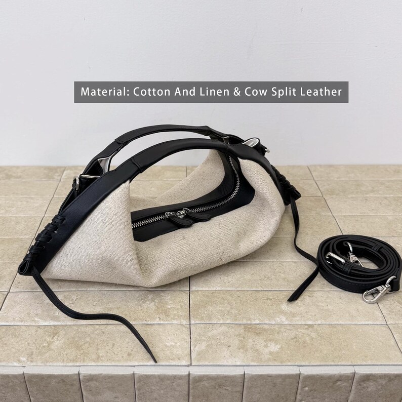 May include: A handbag made of beige cotton and linen with black cow split leather trim, featuring a top zipper closure, integrated handles, and a detachable black leather shoulder strap. Text on the image reads: Material: Cotton And Linen & Cow Split Leather.