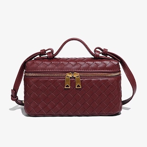 Puede incluir: Un bolso rectangular de color burdeos con un patr&oacute;n tejido. El bolso cuenta con un asa superior, una correa de hombro desmontable y dos cremalleras doradas. El dise&ntilde;o del bolso es compacto y elegante.