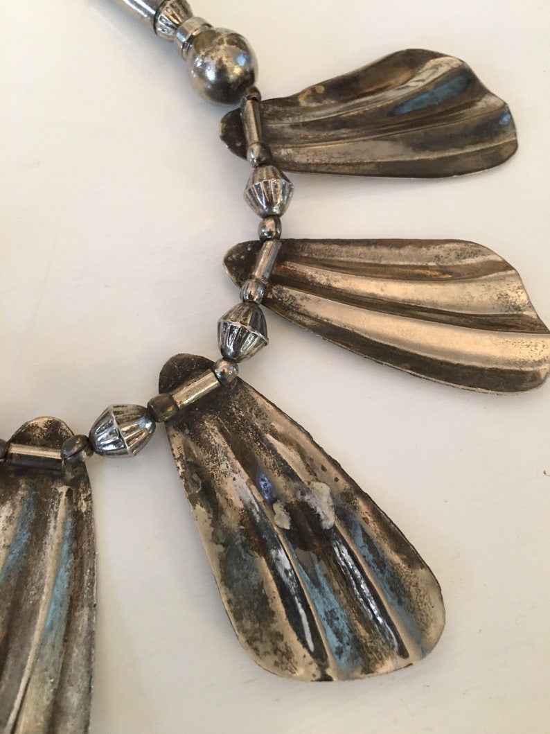 May include: A silver necklace with a series of fan-shaped pendants and small round beads.